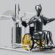 A robotic figure in a wheelchair operates a gym machine designed for rehabilitation or adaptive fitness.